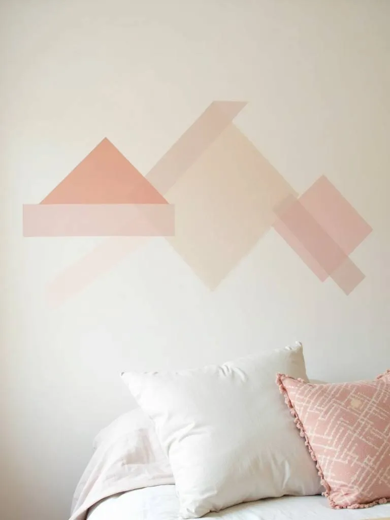 A bedroom wall with geometric wall art created using colorful washi tape, adding a creative touch to the space