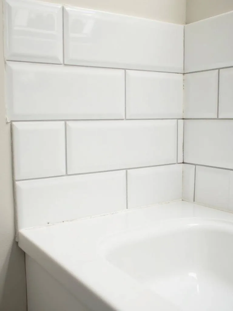 Close-up of a bathroom vanity backsplash with white peel-and-stick subway tiles