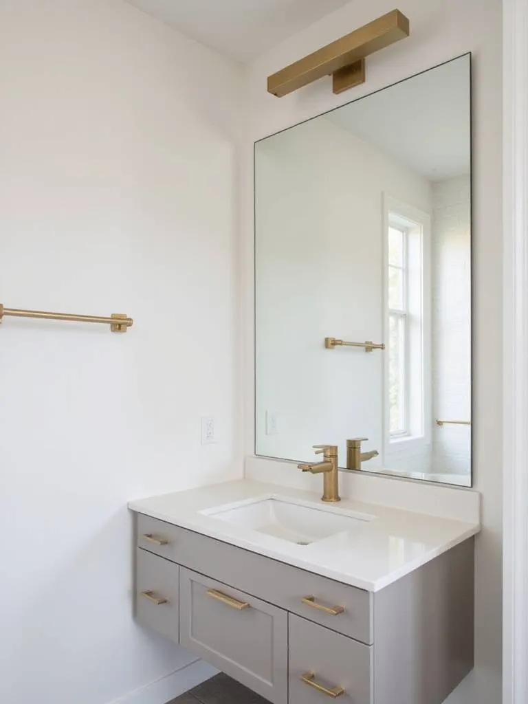 Modern bathroom vanity featuring a consistent brushed gold finish on the faucet, cabinet pulls, towel bar, and light fixture for a coordinated look.