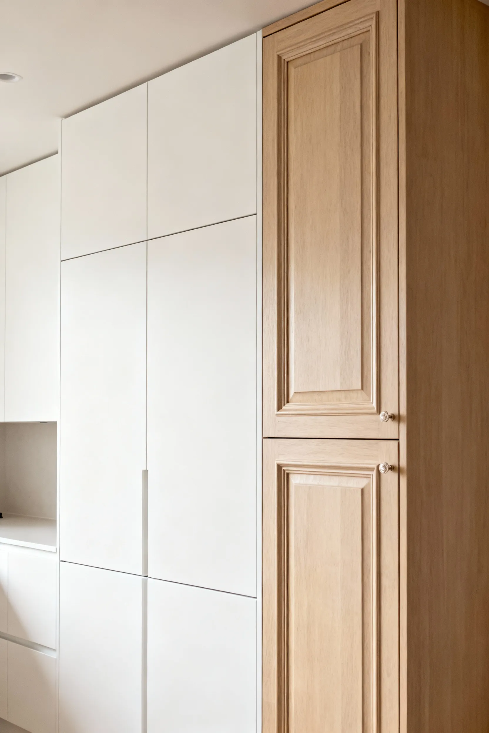 Comparison of frameless white lacquered kitchen cabinets and framed light wood shaker kitchen cabinets, highlighting European design influence and construction differences.