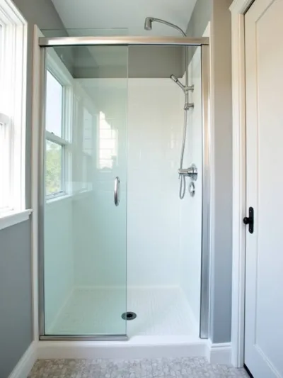 Small, bright bathroom with clear glass shower doors enhancing the sense of openness and spaciousness.