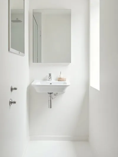 Small, minimalist bathroom showcasing clean lines, uncluttered surfaces, and a serene, clutter-free vibe.