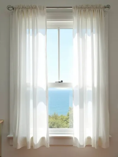 Coastal kitchen window with light and airy white linen curtains.